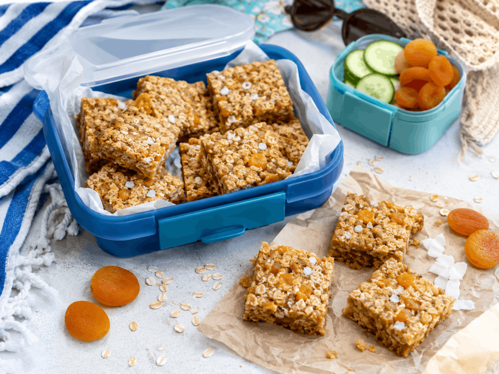 Aprikosen-Kokos-Haferschnitten in einer Lunchbox als süßes Meal Prep für unterwegs im Sommer.